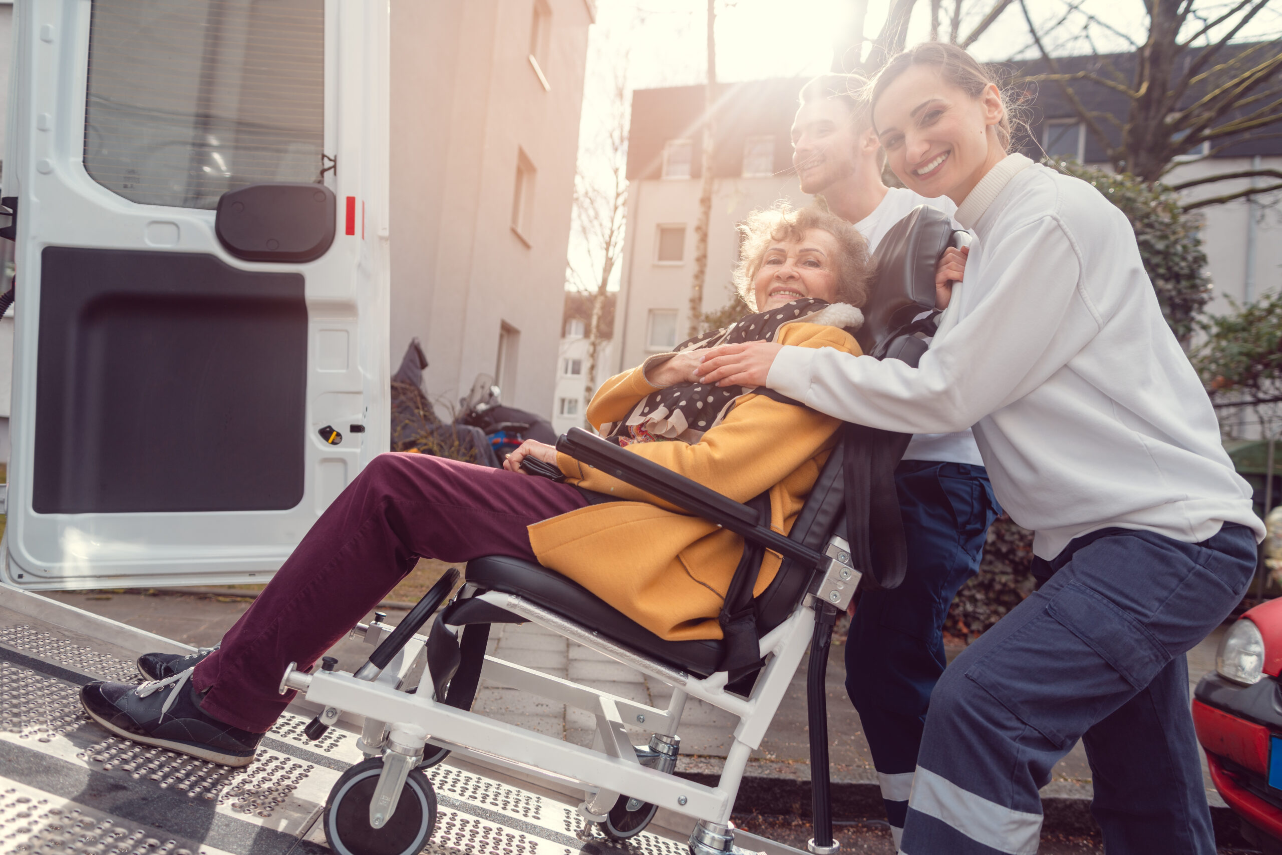 Drivers loading wheelchair patient into transport van for dialysis transportation