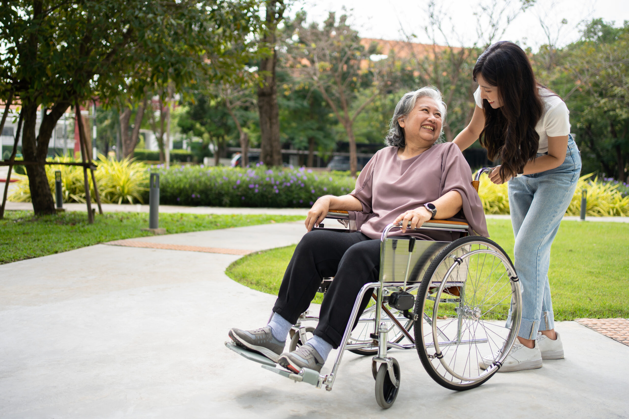 Caretaker pushing elderly in wheelchair to medical appointment transportation provider